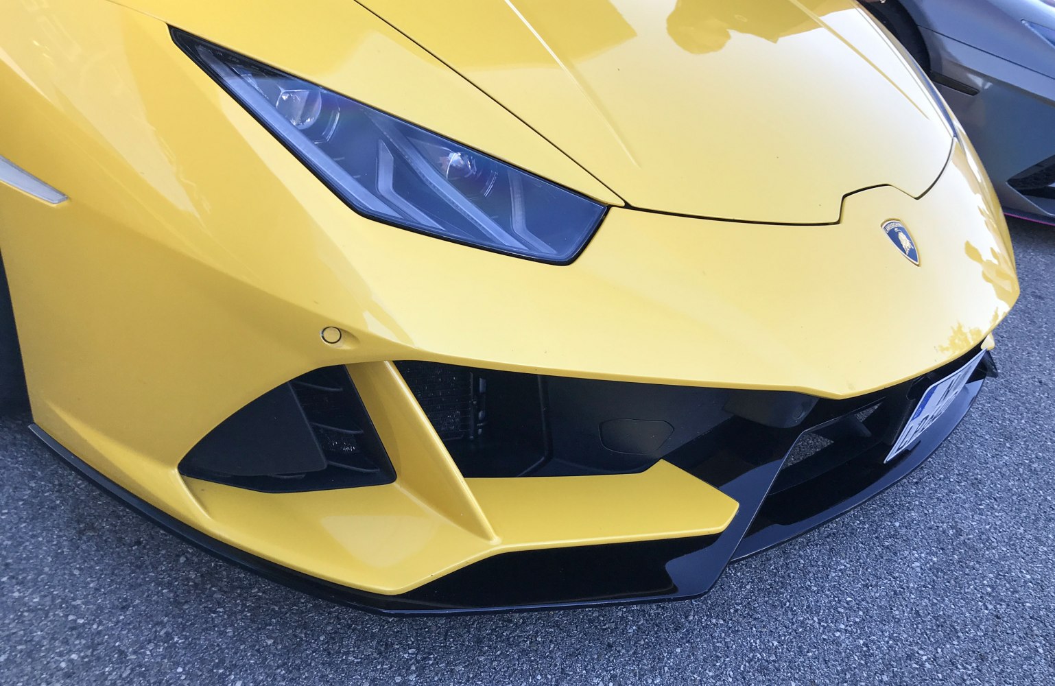 Close-up of sharp headlight and aerodynamic front bumper in yellow paint