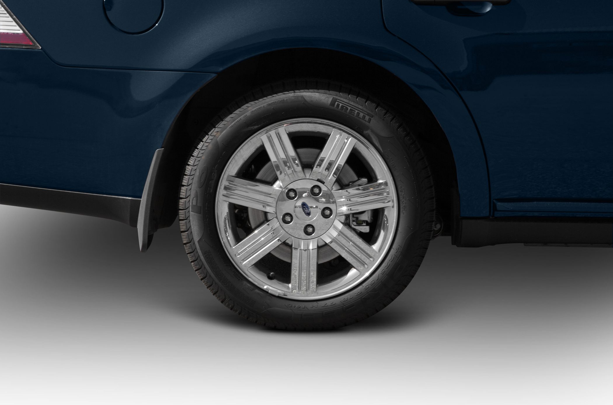 Chrome alloy wheel with Pirelli tire on rear side of car