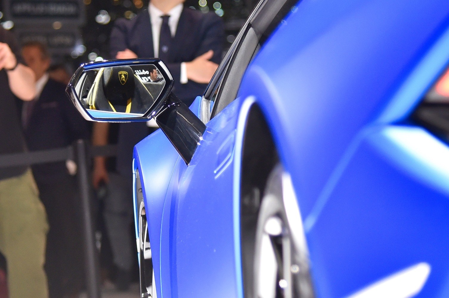 Side mirror showing interior seat with logo, blue exterior door.