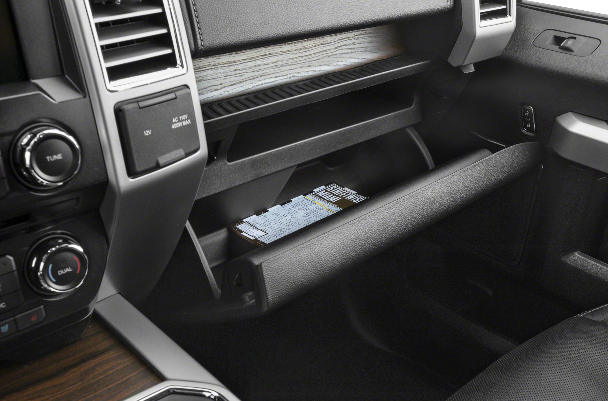 Open glove compartment with power outlets and wood grain dash trim