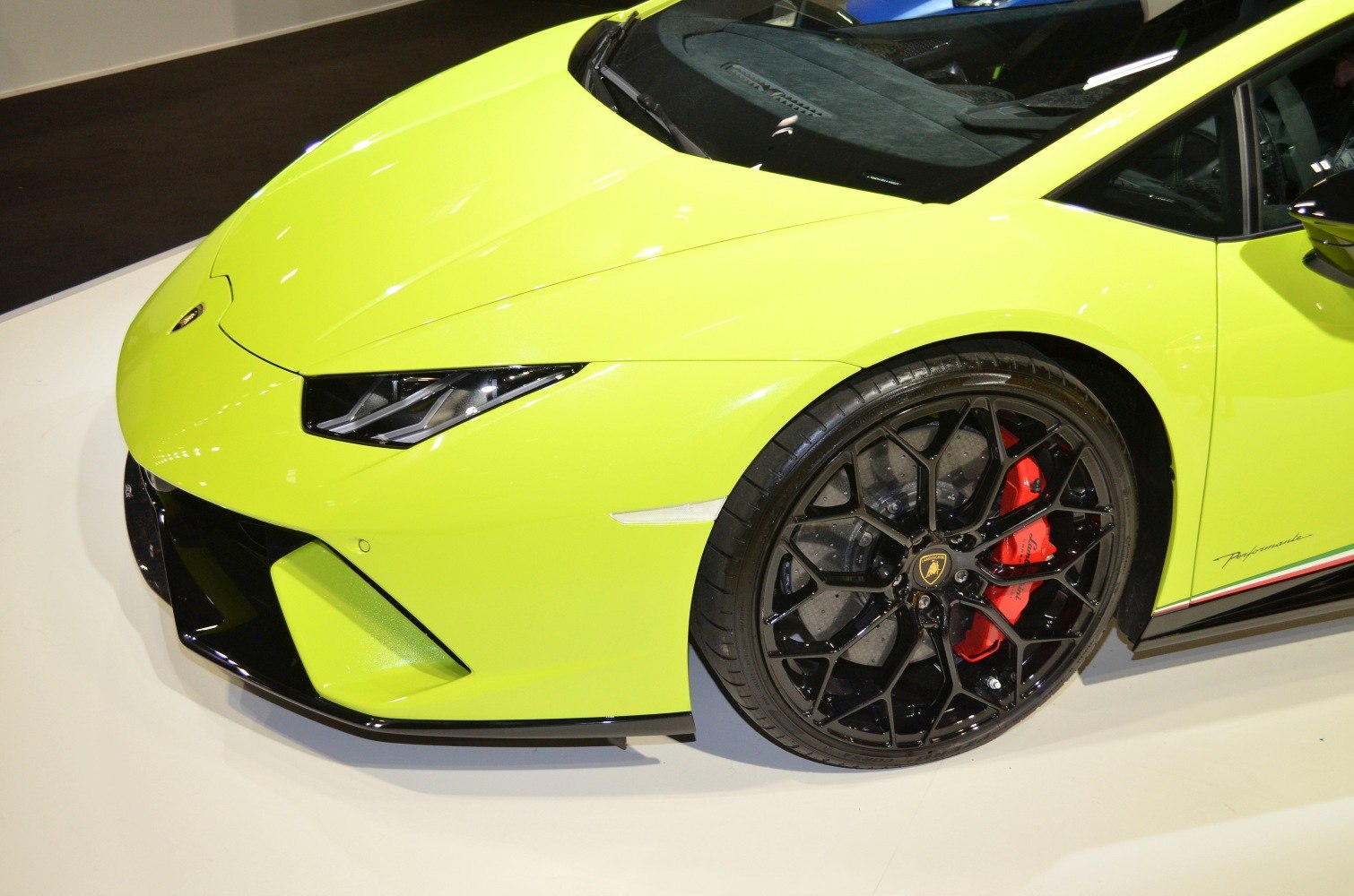 Close-up of sharp headlights and black alloy wheel with red brake caliper