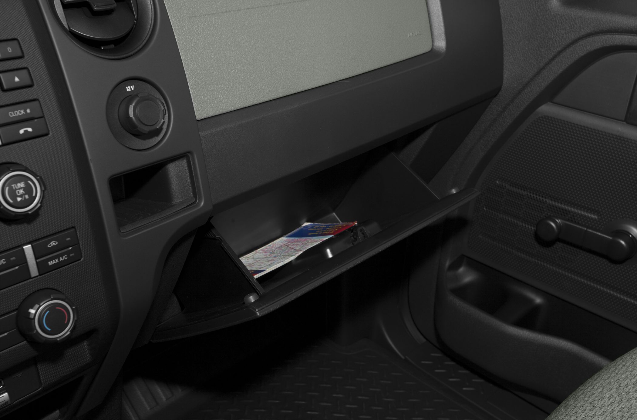 Open glove compartment in truck interior with map and dashboard controls