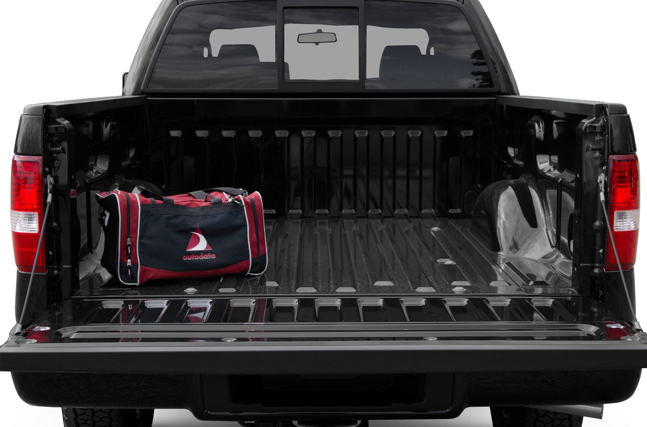 Open pickup tailgate with black bed and red sports bag