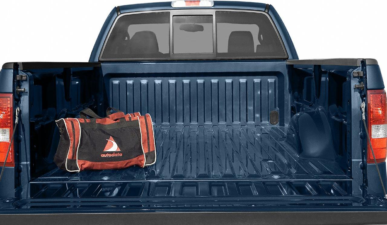 Open pickup truck bed with utility bag and rear cab window.