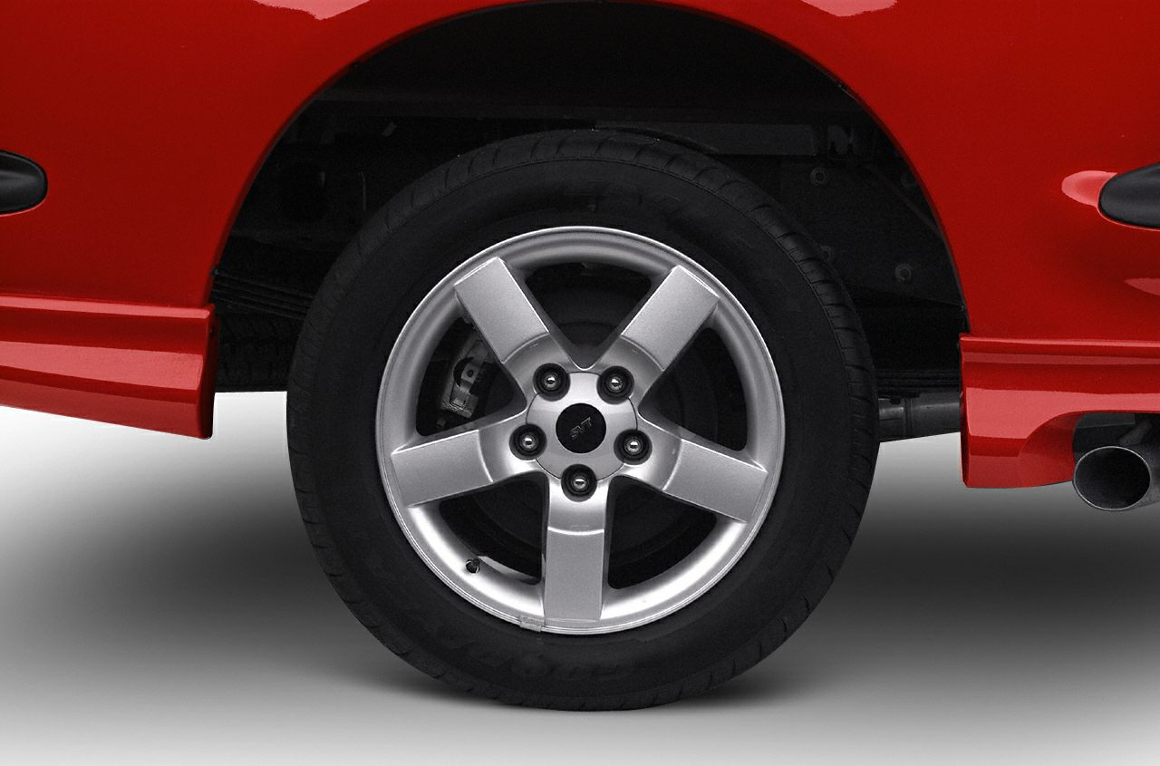 Silver five-spoke alloy wheel on red truck with visible exhaust pipe