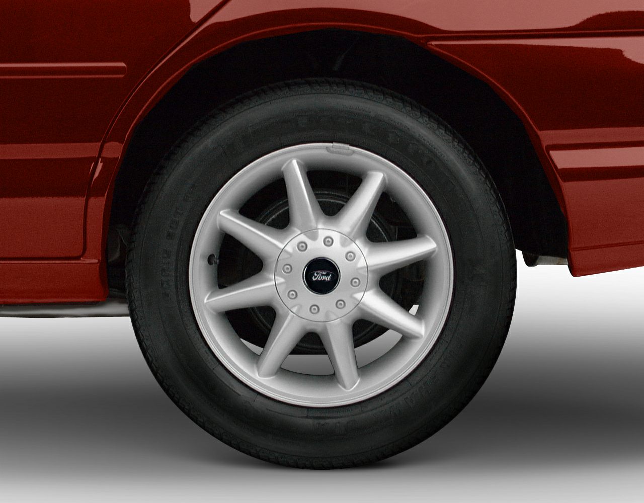 Alloy wheel with tire on red vehicle body