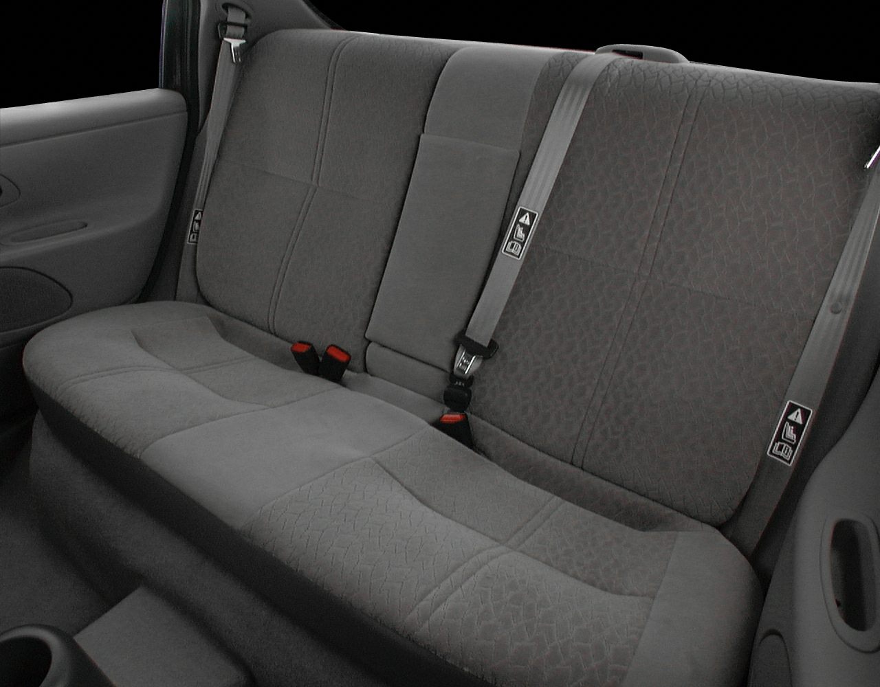 Rear seat upholstery with seat belts and fabric pattern.