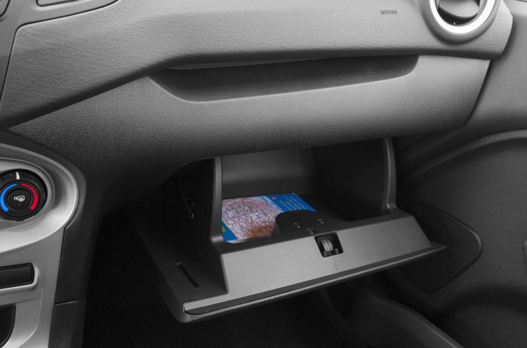 Open glove compartment with map, dashboard air vent, and climate control knob