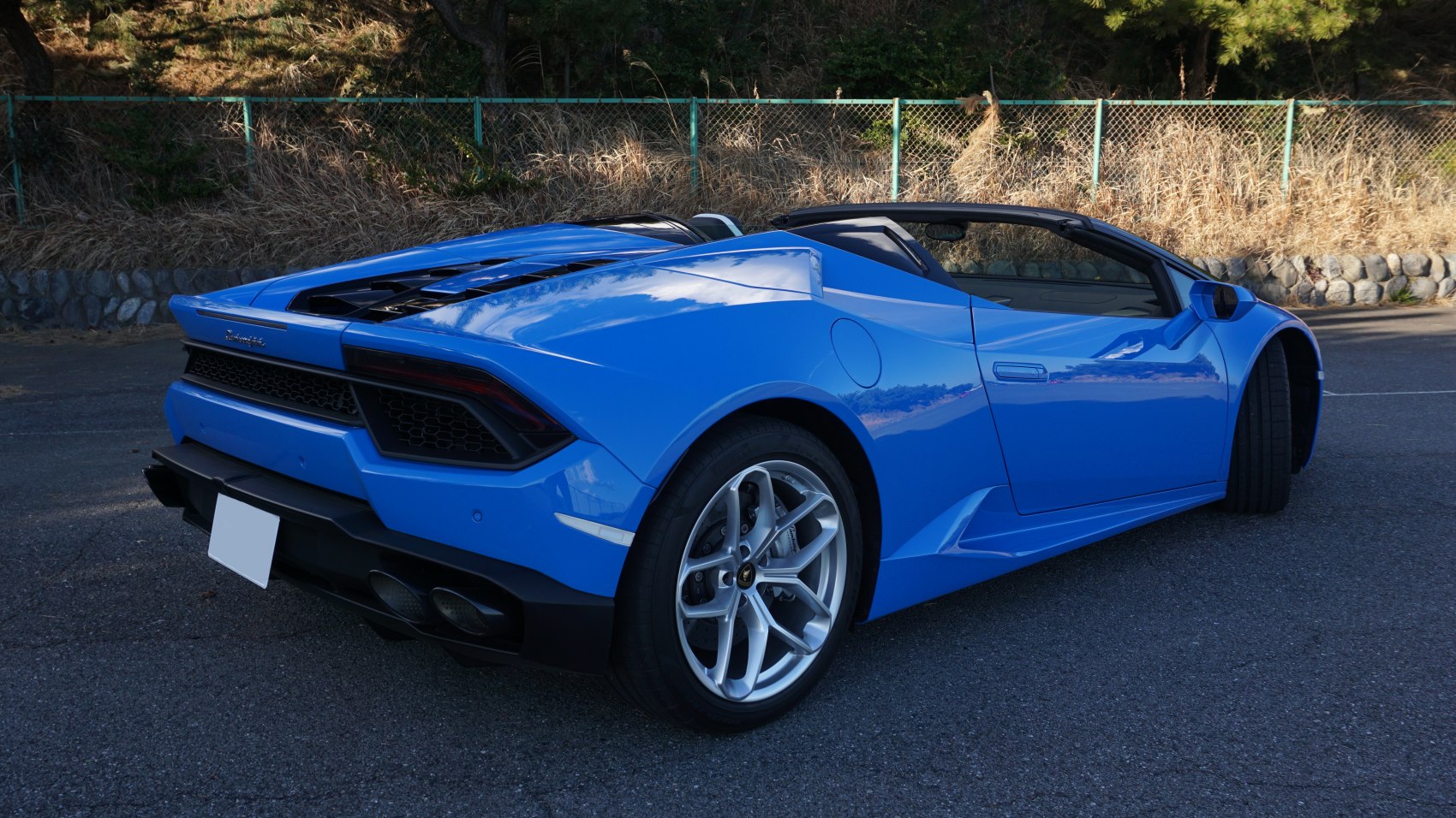 Rear and side view of blue convertible sports car with aerodynamic design and alloy wheels