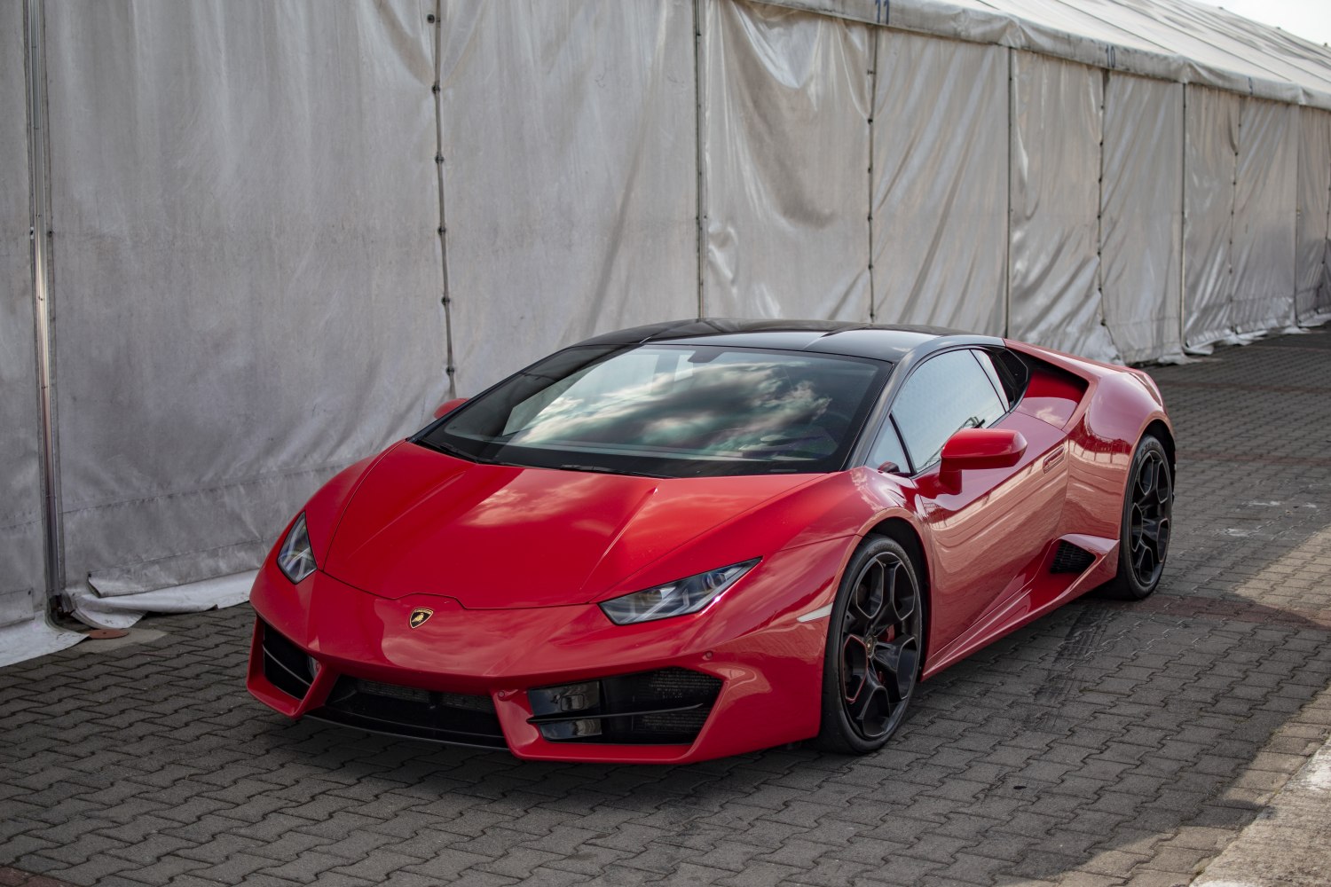 Red sports car with sharp headlights and black alloy wheels in front-side view