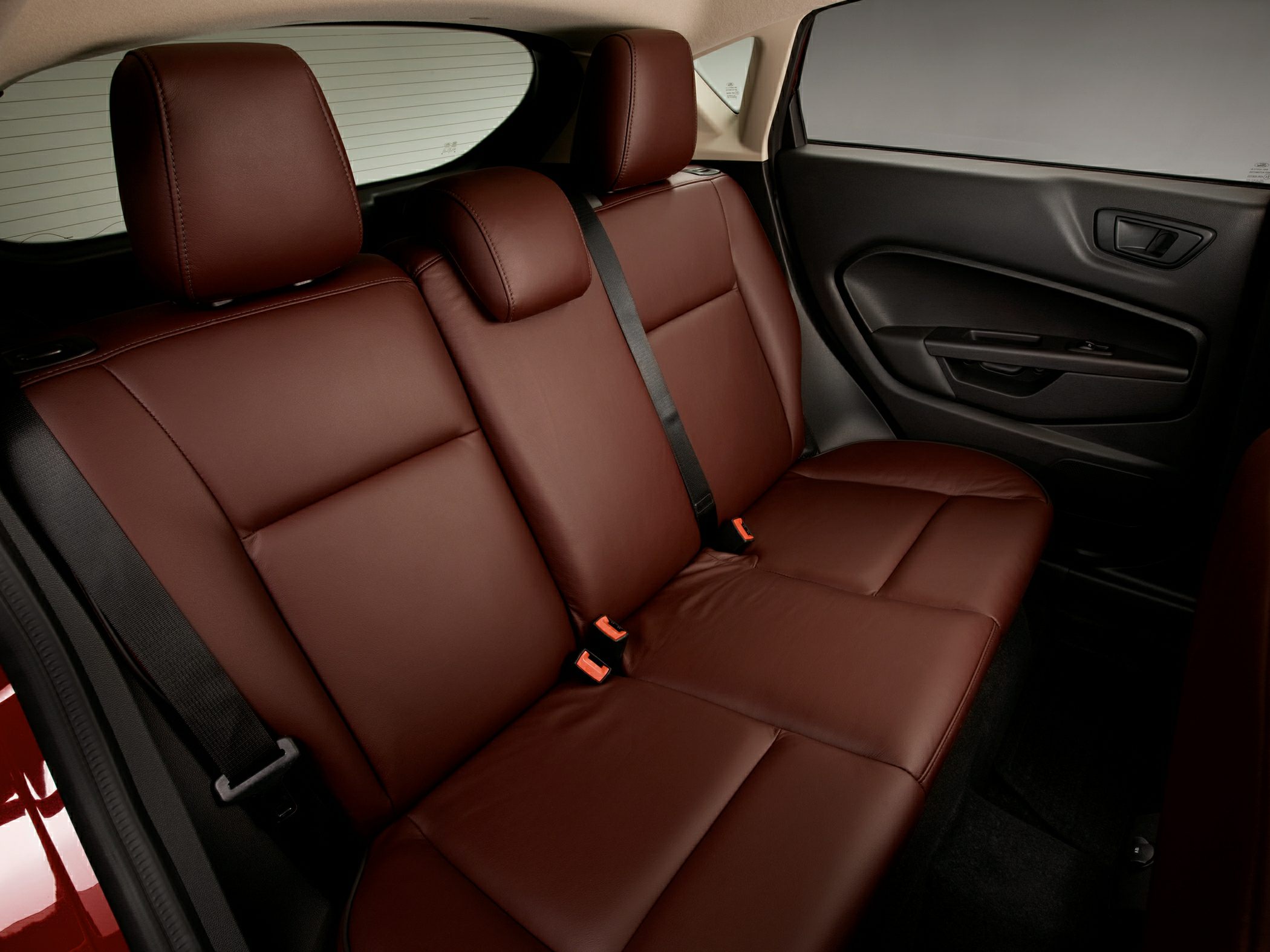 Brown leather rear seat with integrated seat belts and door panel.