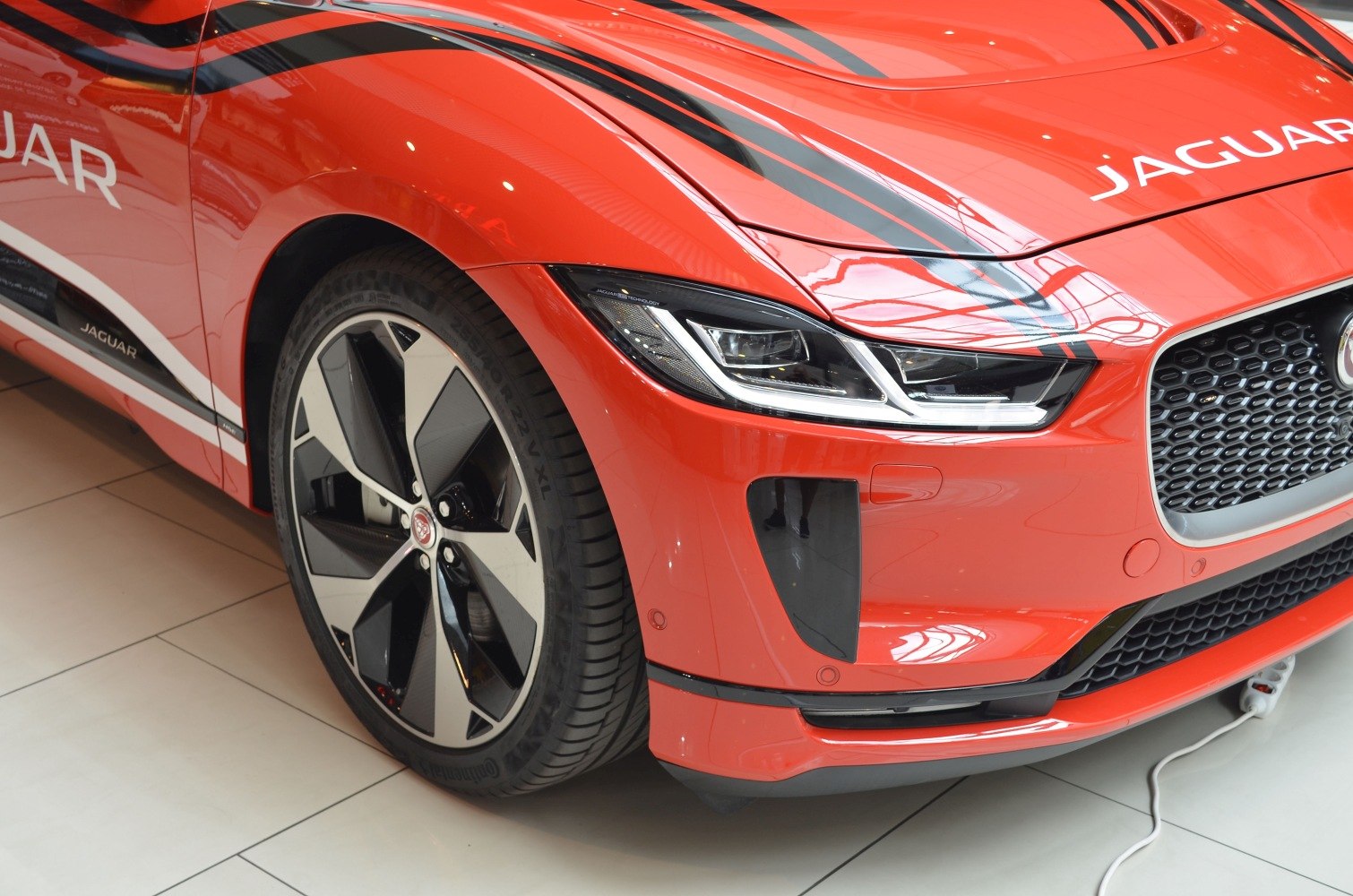 Close-up of front wheel, headlight, and grille with red paint and racing stripes