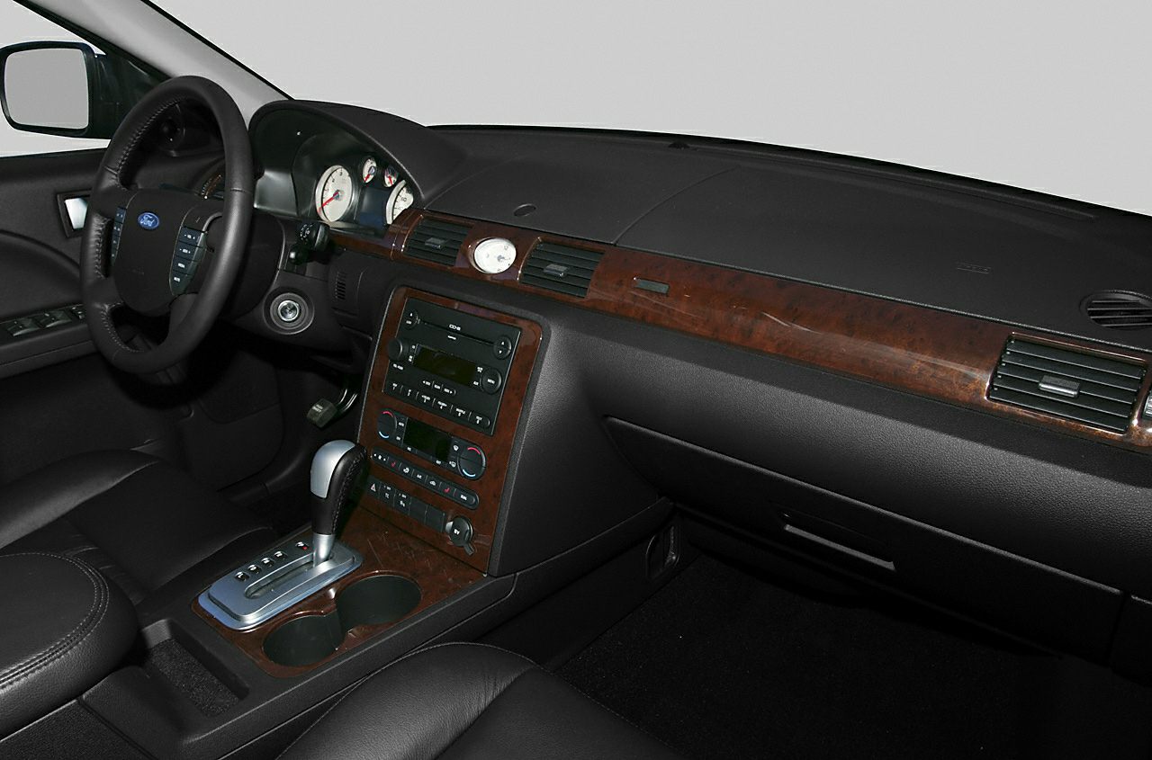 Car interior featuring wood trim, leather seats, and dashboard with analog gauges.