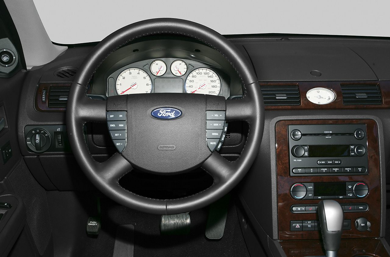 Steering wheel with controls, dashboard gauges, wood-trimmed center console
