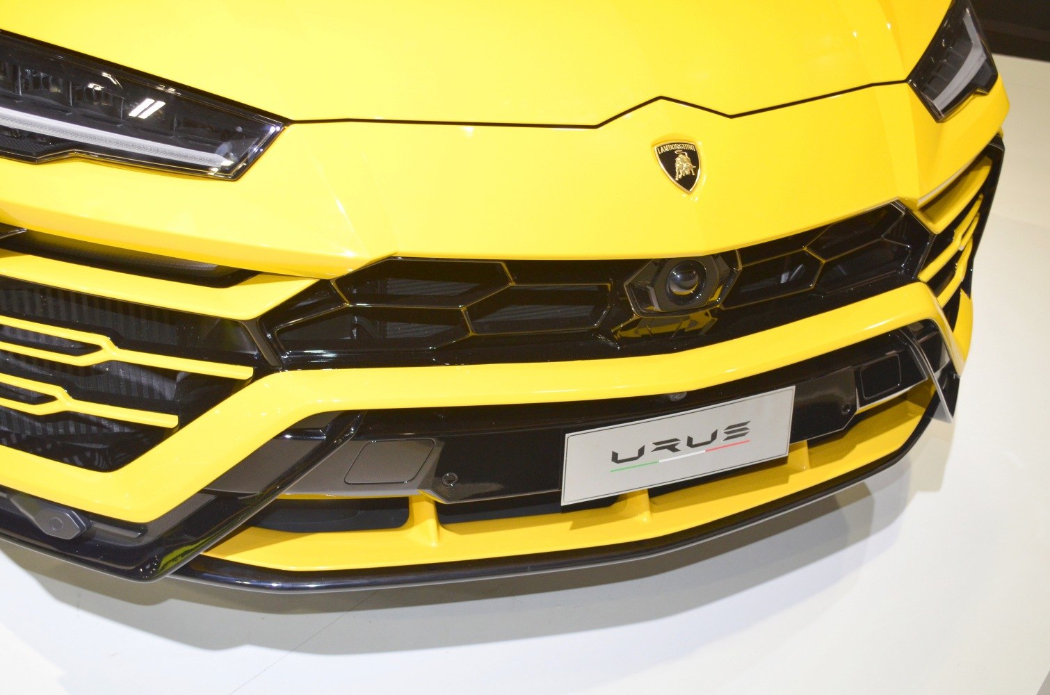 Close-up of grille and LED headlights on a yellow luxury SUV front.