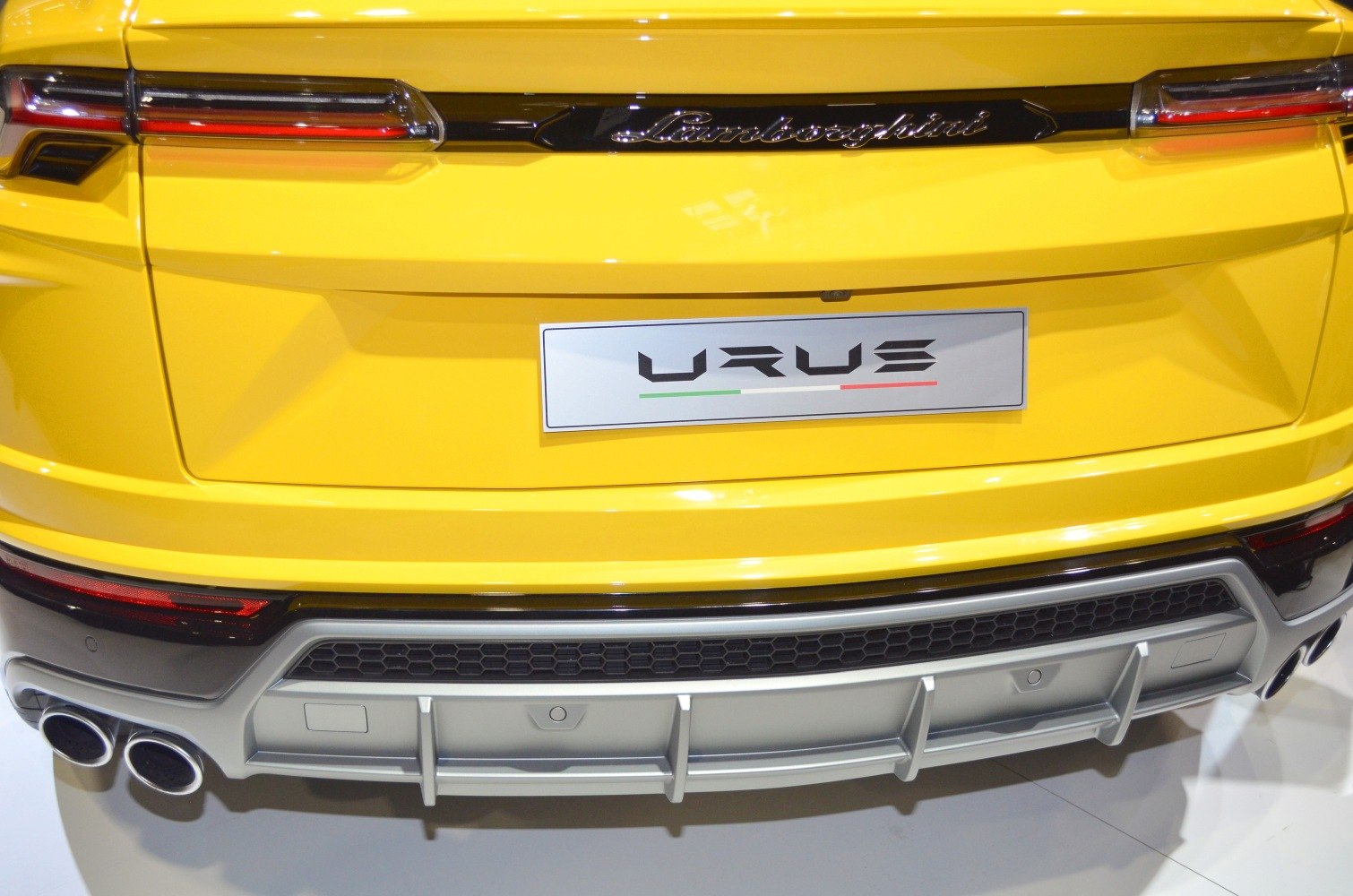 Lamborghini Urus rear with quad exhausts, LED tail lights, and diffuser in yellow.
