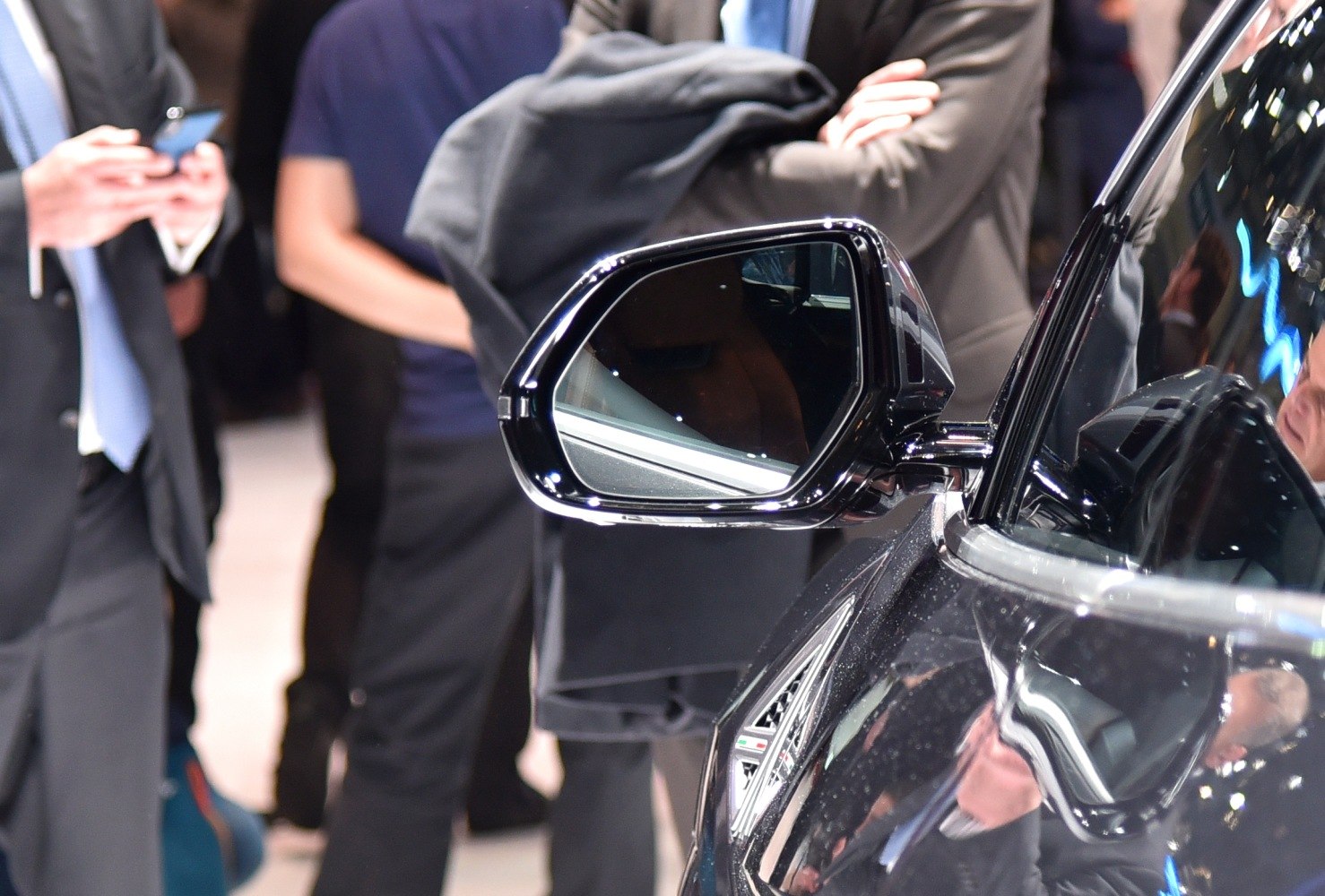 Close-up of luxury SUV side mirror with reflective glass and sleek black housing.