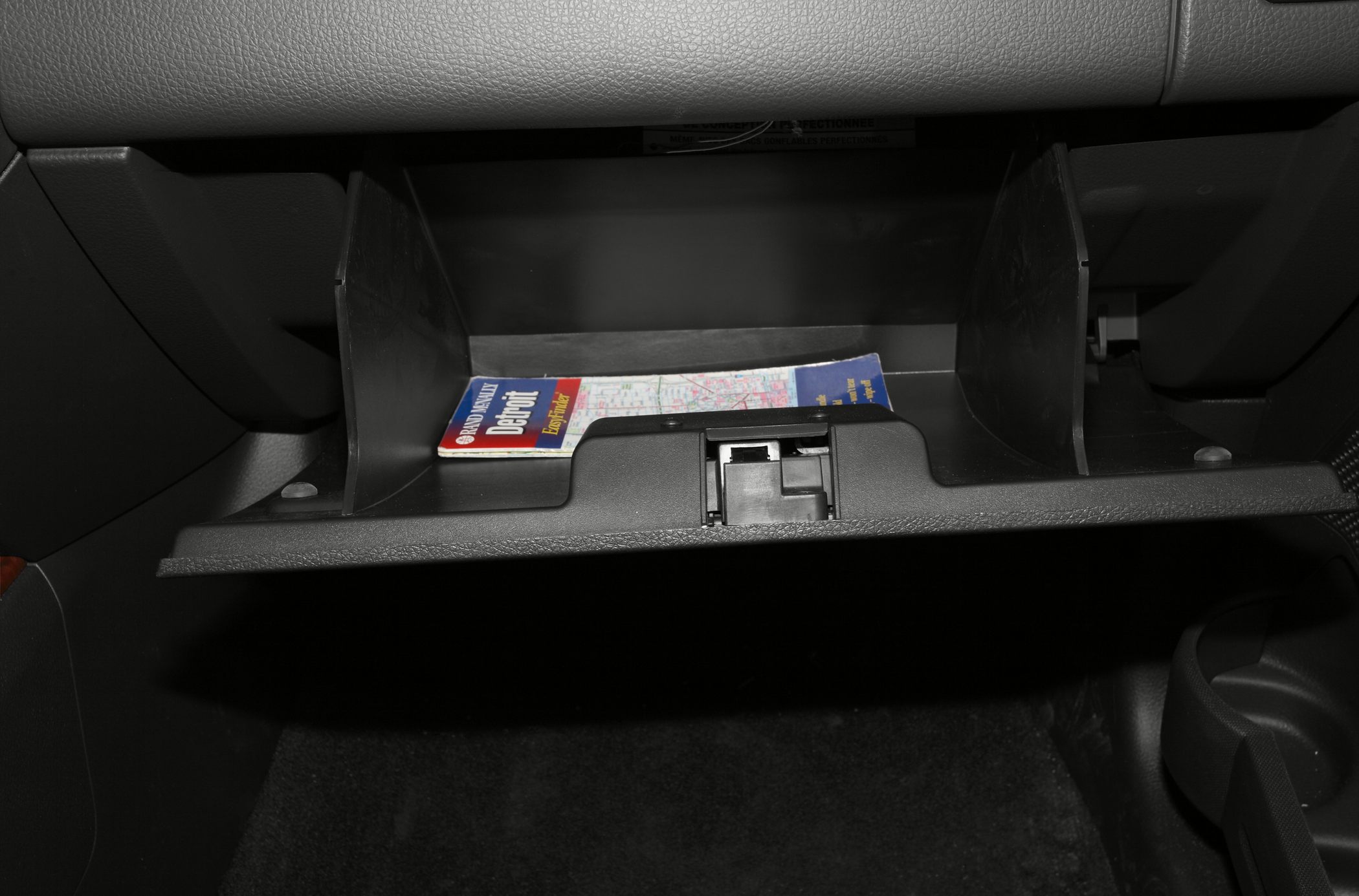 Opened glove box storage compartment with map inside