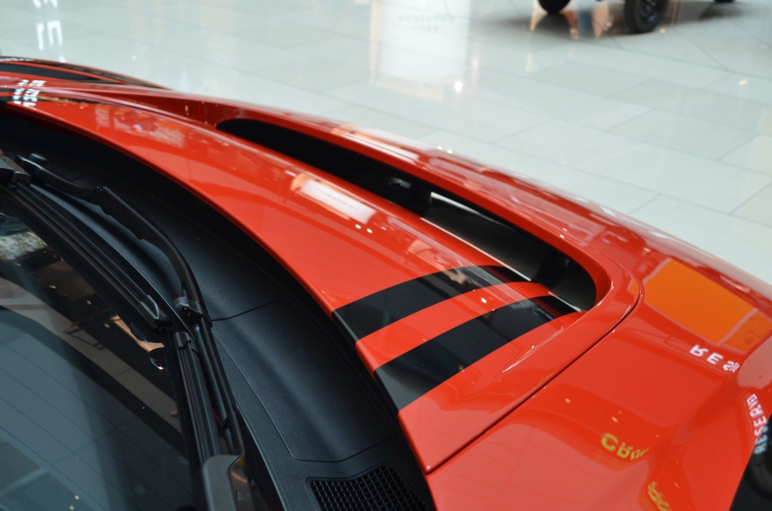 Close-up of hood vent with black racing stripes and windshield wiper