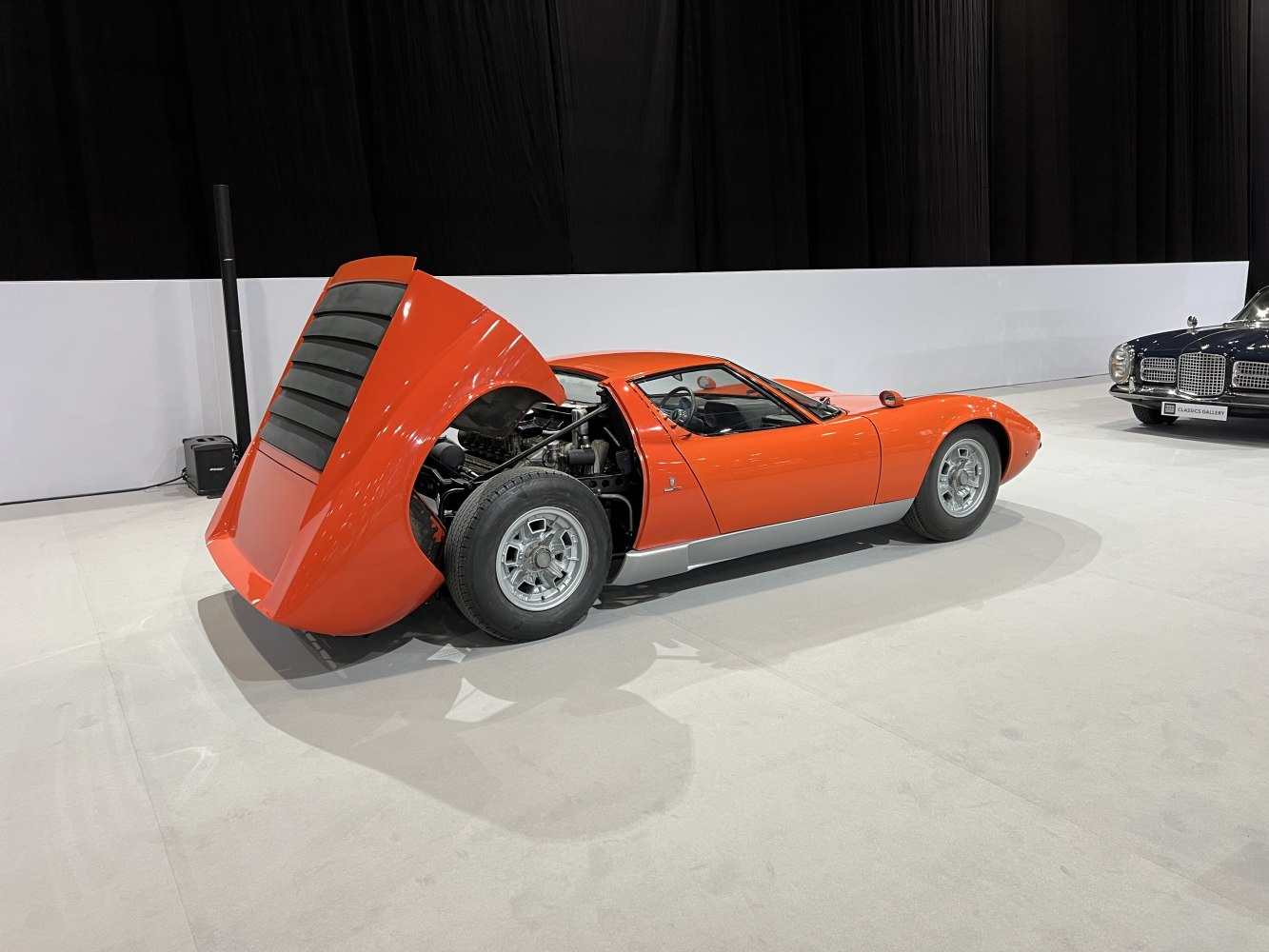 Rear engine with large pop-up hatch and distinctive wheels on a low-profile vintage sports coupe.