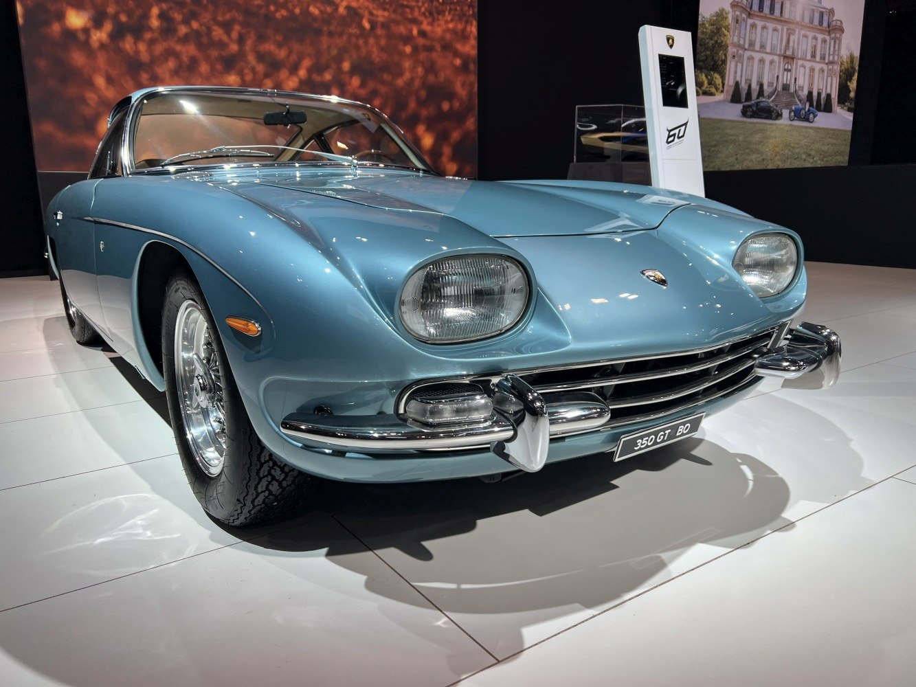 Blue vintage sports car with smooth curves, round headlights, and chrome bumpers.