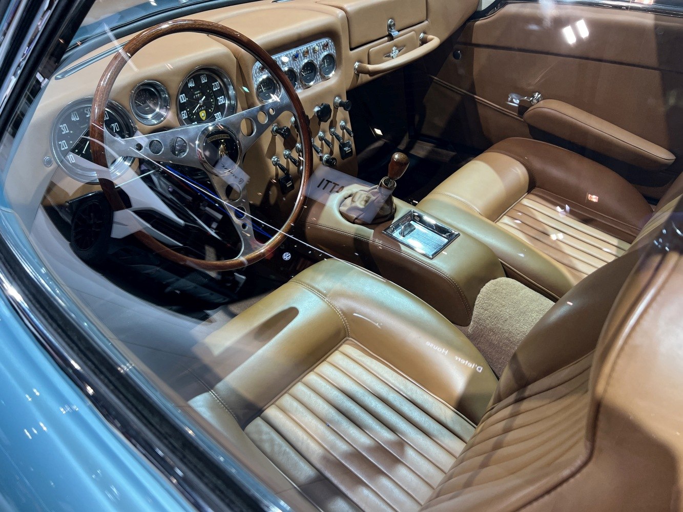 Vintage steering wheel, analog gauges, leather seats, and manual gear shift.