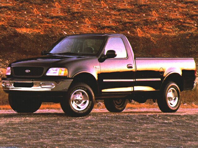 Front side view of a regular cab pickup truck on rugged ground