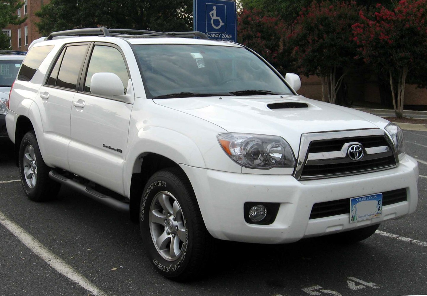 White mid-size SUV with hood scoop, chrome grille, alloy wheels, and side steps