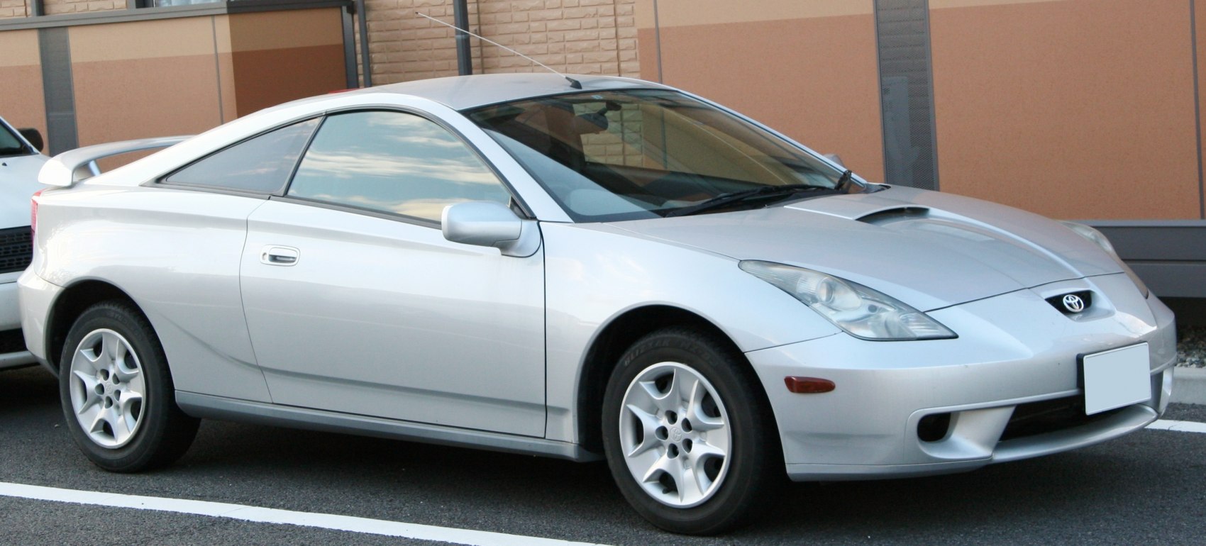 Silver sports coupe with rear spoiler and hood scoop, aerodynamic design.