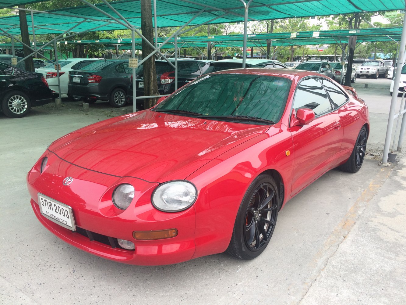 Sleek red coupe with distinctive round headlights and black alloy wheels.
