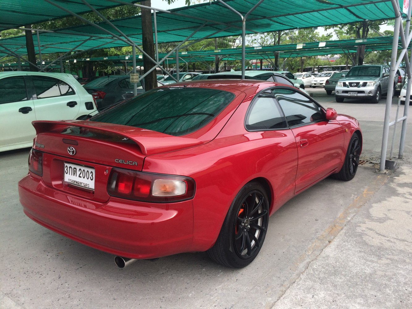 Red coupe with rear spoiler, black rims, and tinted windows