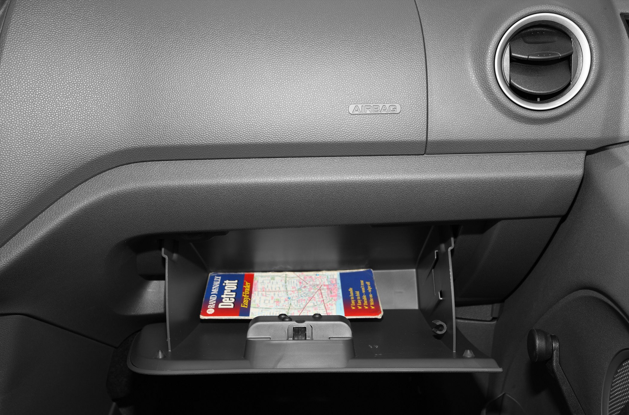 Open glovebox with map inside and dashboard airbag panel