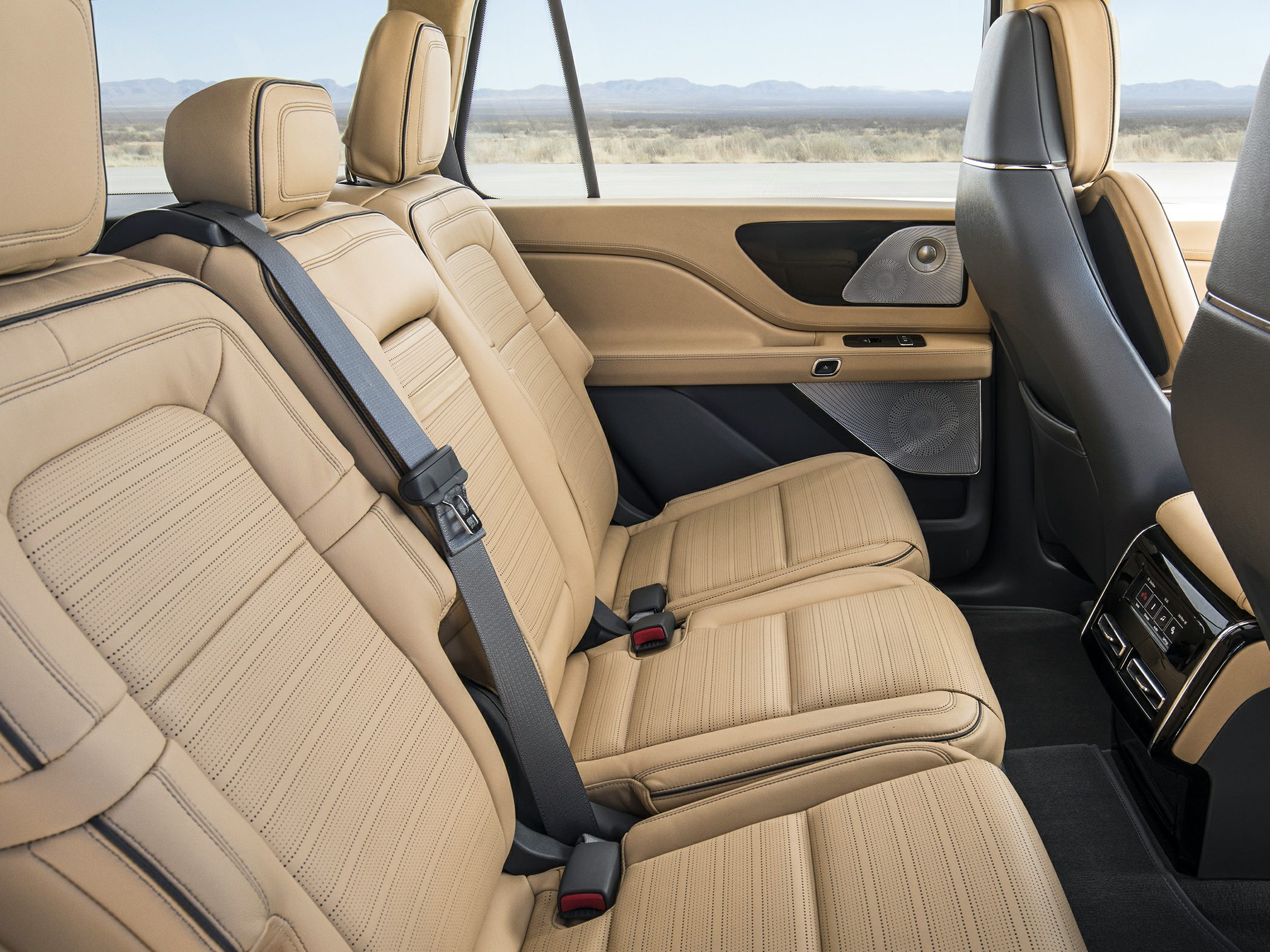 Tan leather rear seats with detailed stitching and built-in speaker panels