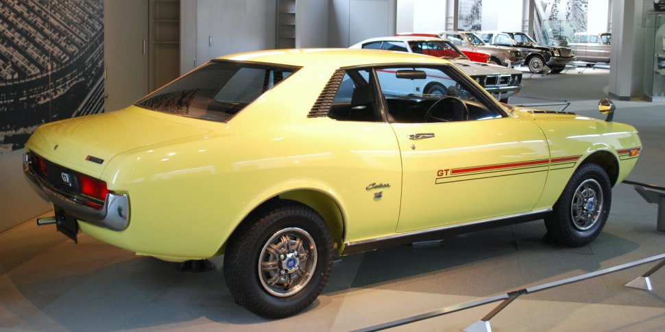 Yellow 1970s sports coupe with GT side stripes and chrome wheels