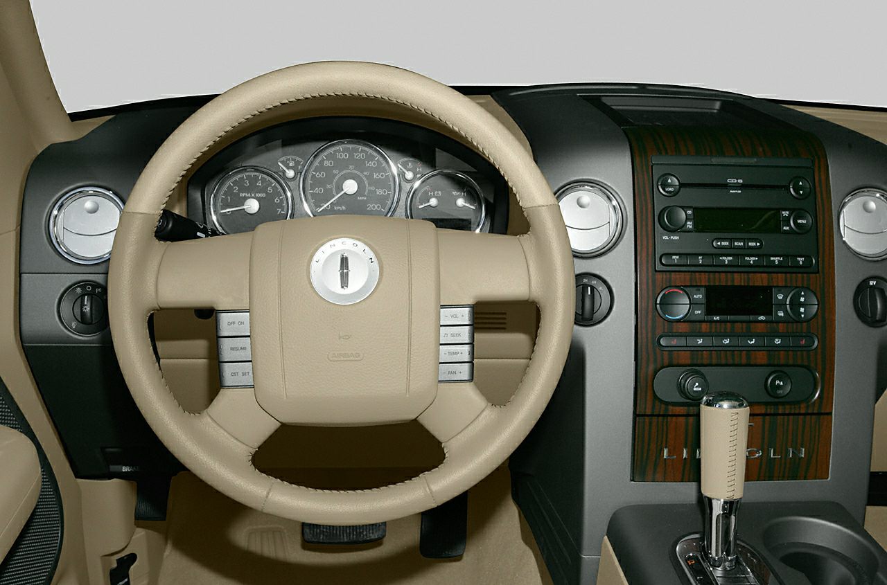 Beige leather steering wheel and wood-trimmed dashboard with controls.