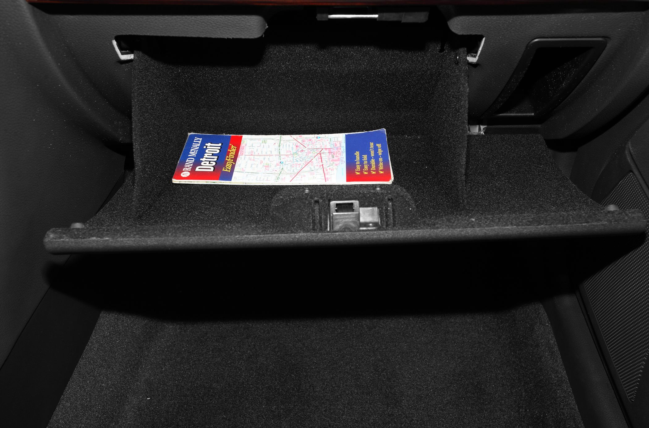 Open glove compartment with a map inside in a car interior.
