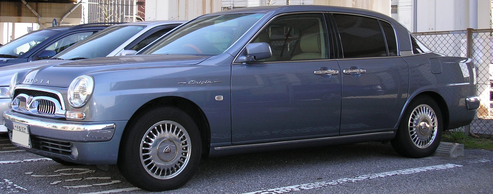 Retro front grille, round headlights, chrome bumpers, Origin badge, sleek sedan profile