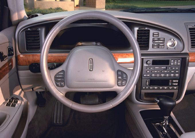 Steering wheel, wood-trimmed dashboard, and center console with controls.