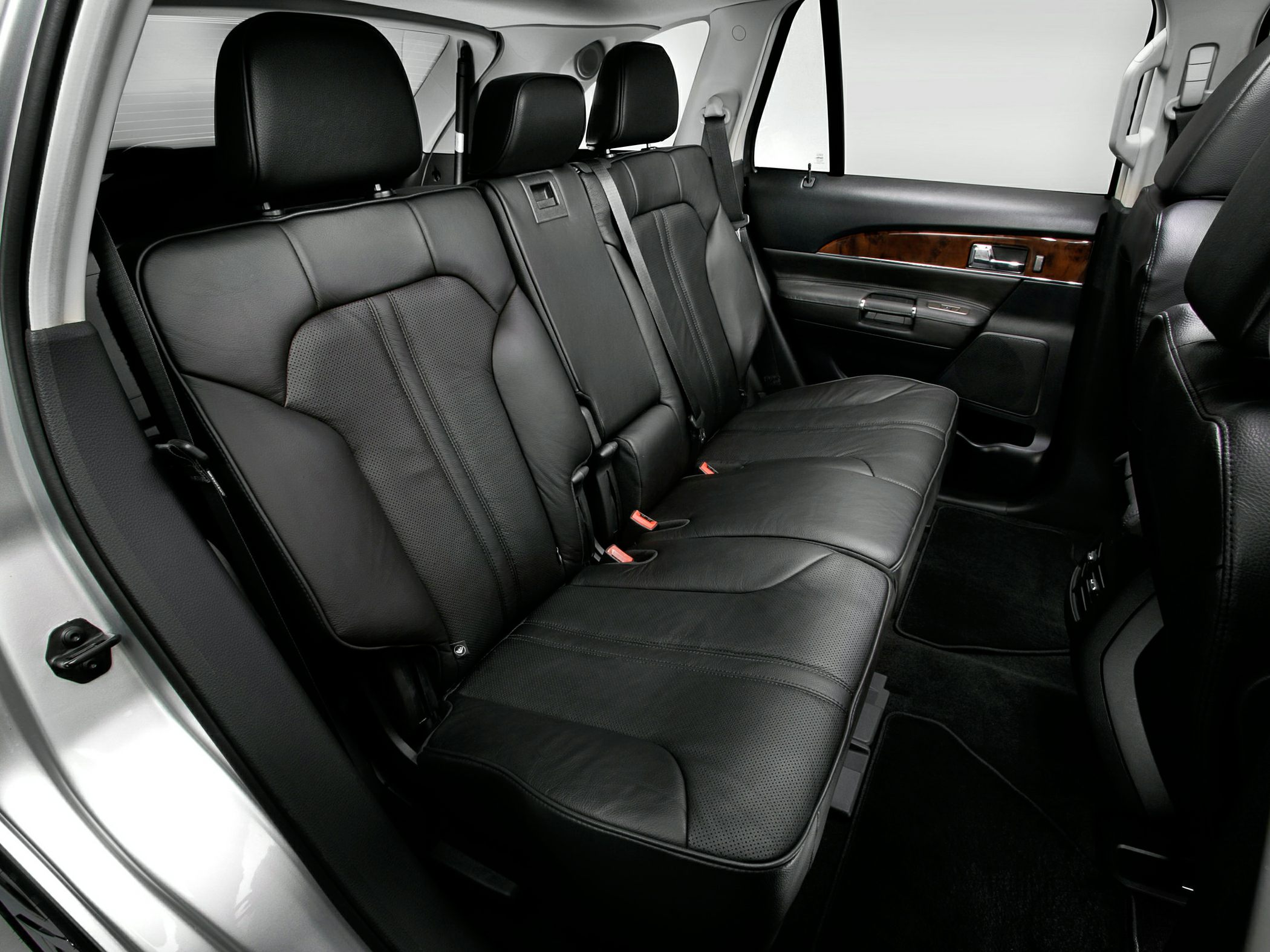 Rear seating with black leather upholstery and wood trim door panel