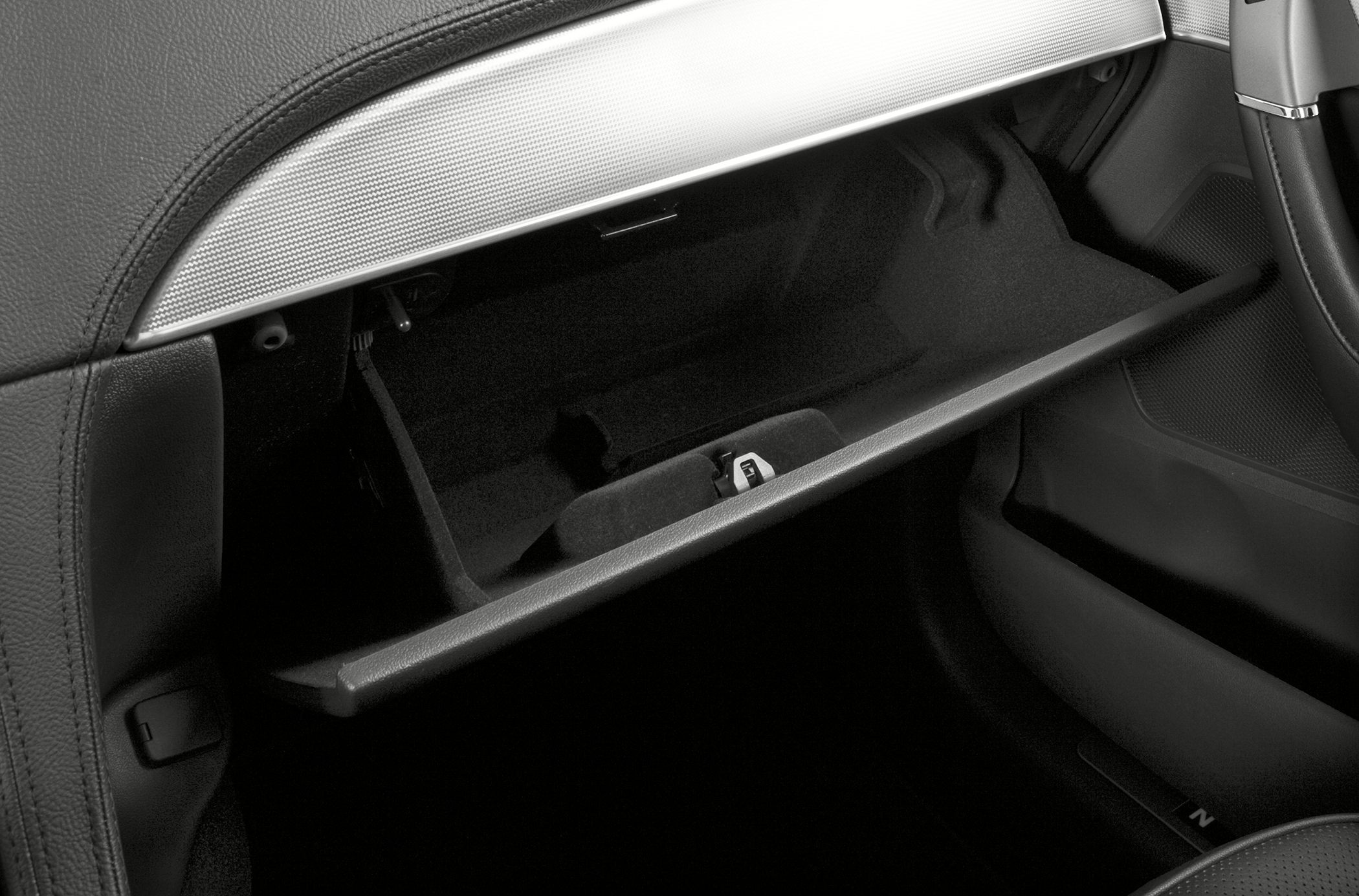 Open glove compartment with black interior and silver dashboard trim