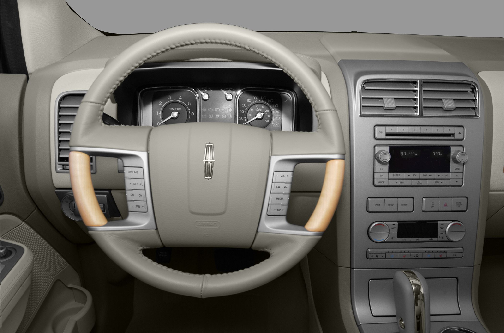 Wood-trimmed steering wheel with control buttons; dashboard with radio and climate controls