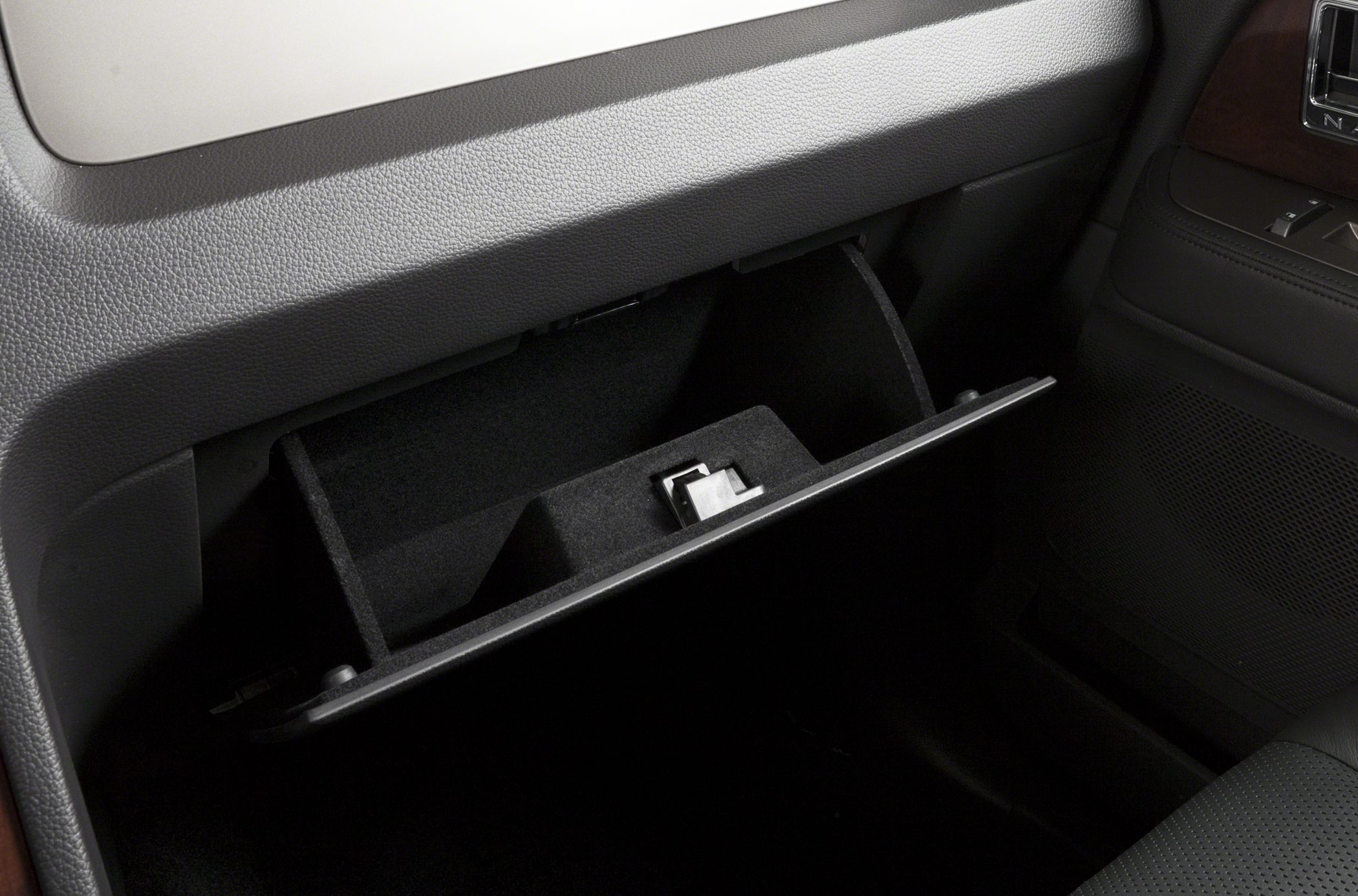 Car interior glove compartment with divided storage and textured surfaces.