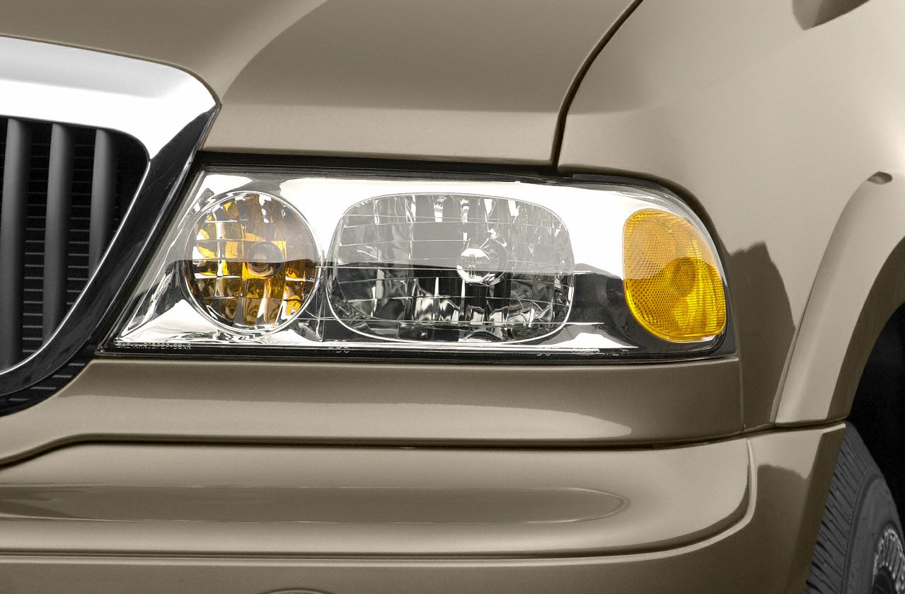 Close-up front headlight with amber turn signals on beige vehicle body.