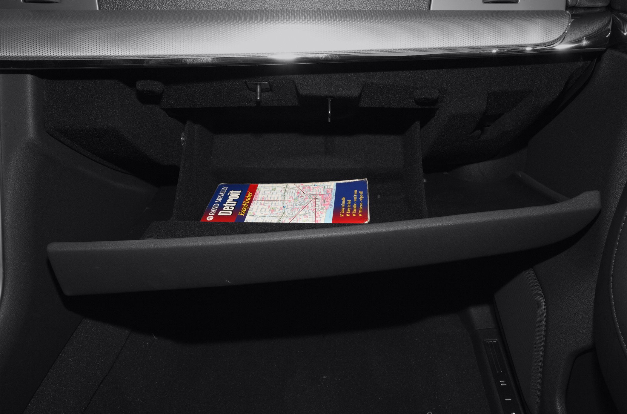 Opened glove compartment with map inside, black interior details