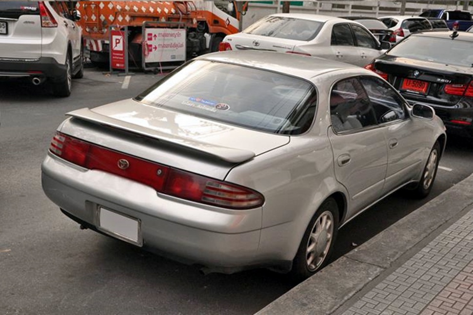 Rear view of a 1990s mid-size sedan with rear spoiler and integrated tail lights