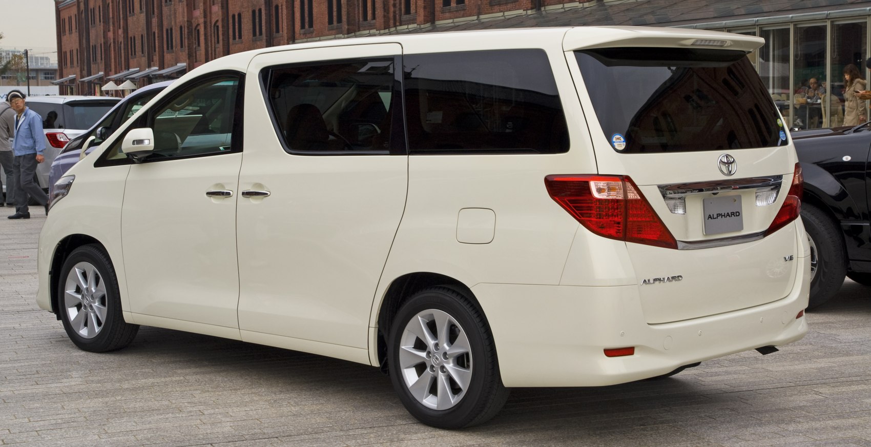 White minivan rear side view with sliding door and detailed tail lights.