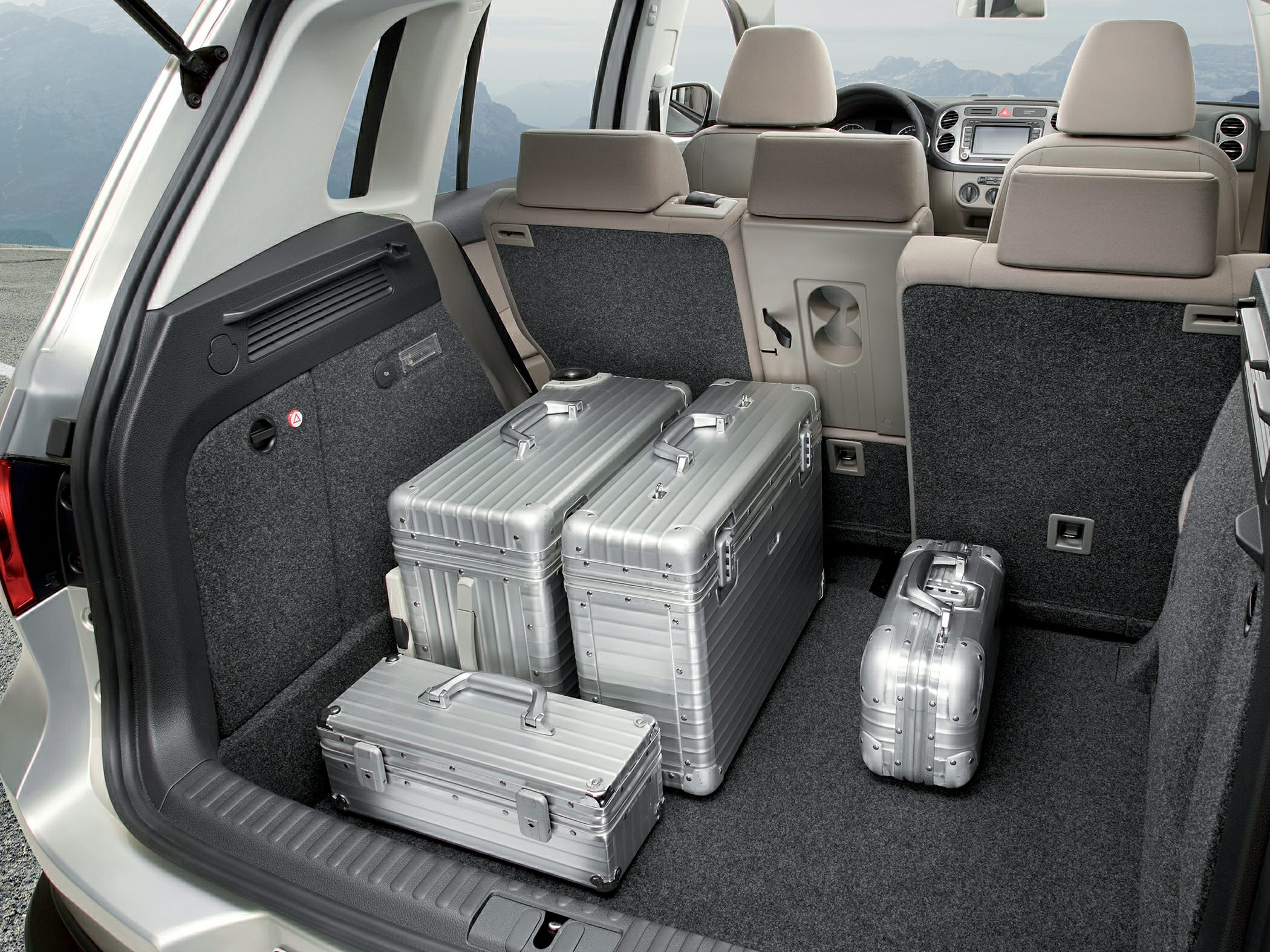 SUV cargo area with folded rear seats and silver hard-shell suitcases