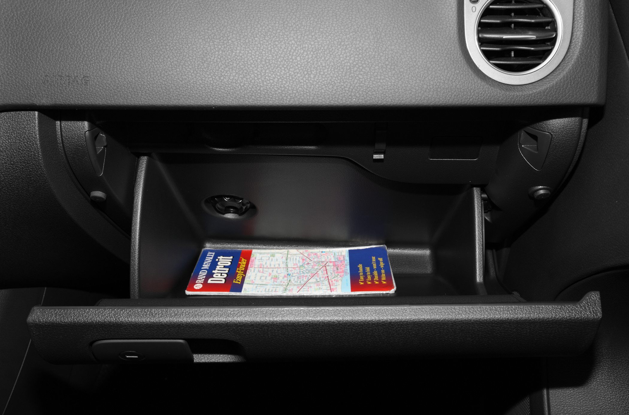 Open glove compartment with map inside in car interior