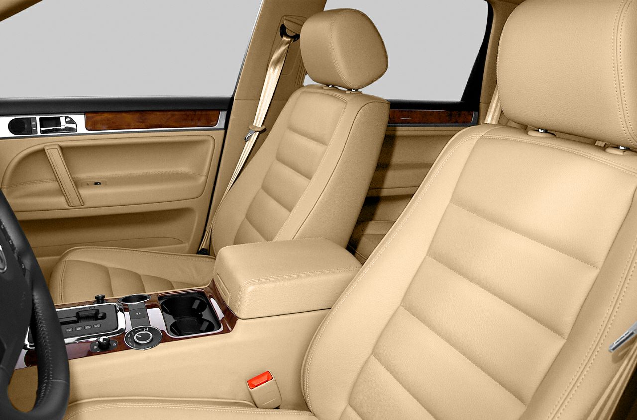 Beige leather seats with wooden trim and central console cup holders and controls.