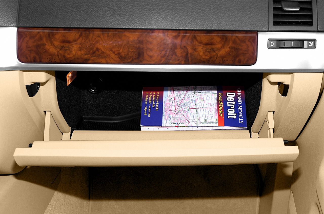 Open glove box with beige panels and wood trim interior